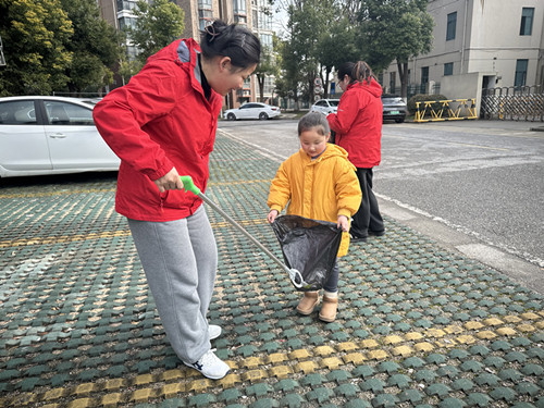 堰桥实幼：清扫小区垃圾，共…